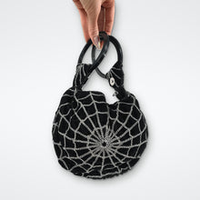 Load image into Gallery viewer, Hand holding black velvet spiderweb purse by its ring handles, showing size of the gothic witchy bag
